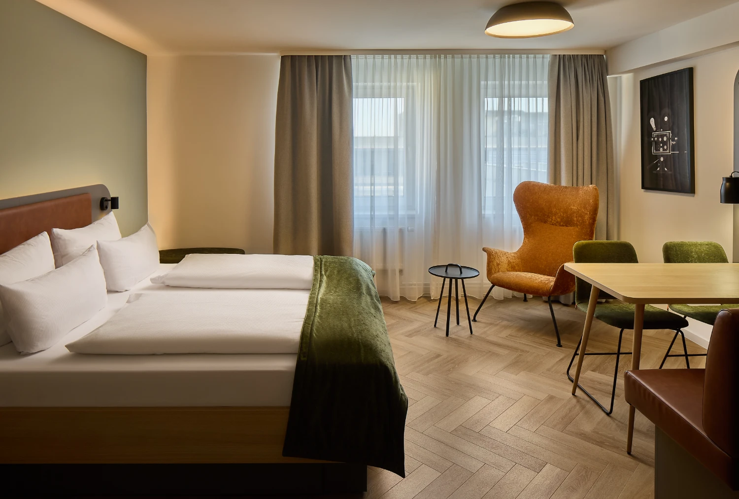 Modernes Hotelzimmer mit Doppelbett, Sitzecke und großem Fenster.
