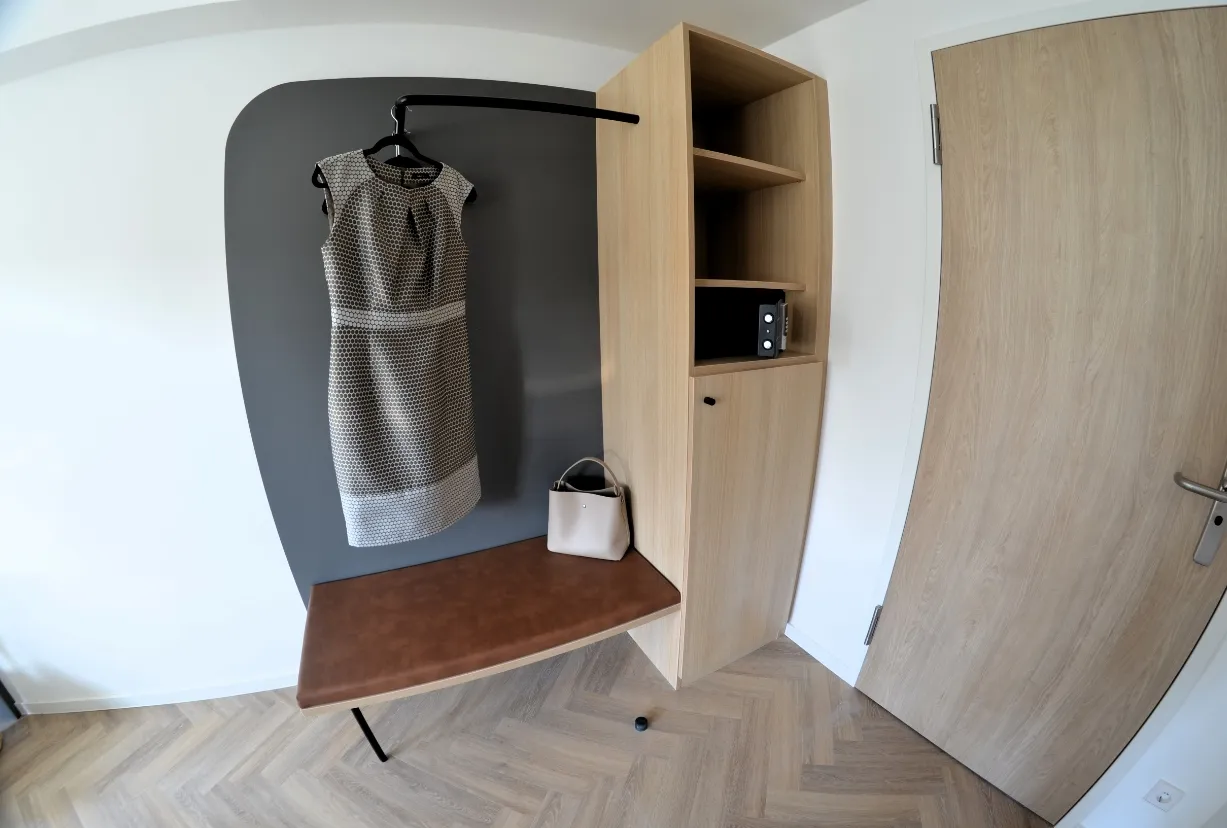 Garderobenbereich im Dreibettzimmer mit Kleiderhaken, Sitzbank, Regal und Mikrowelle