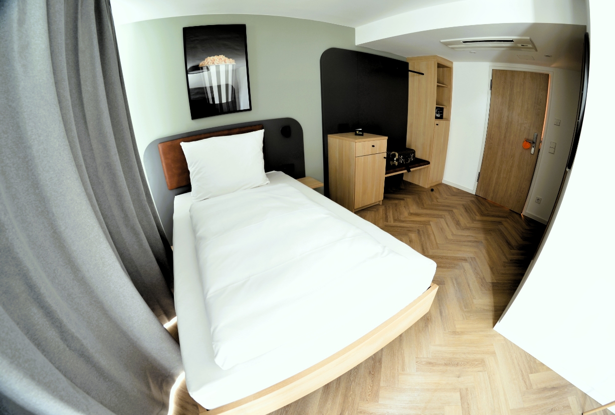 Modern eingerichtetes Einzelzimmer mit Einzelbett, Holzfußboden, Schreibtisch und Wandkunst