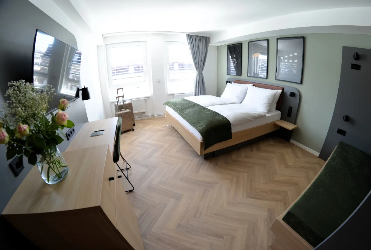 Helles Vierbettzimmer mit Doppelbett, Stockbett und Schreibtisch im Cinema City Hotel