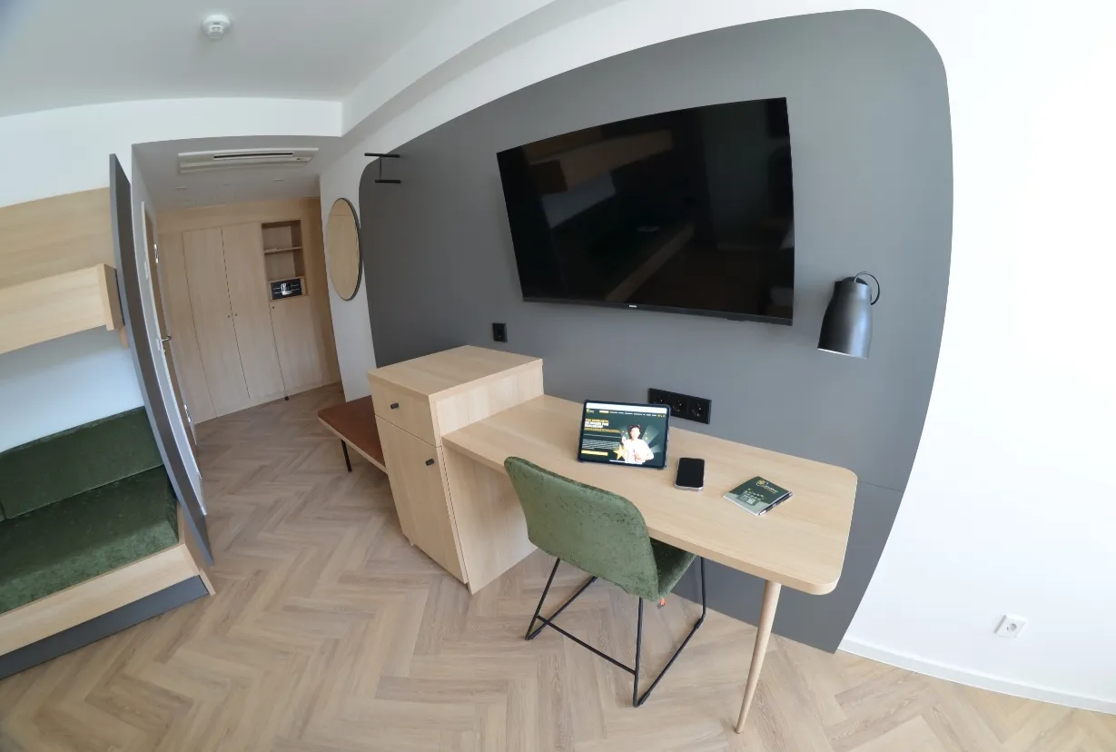 Schreibtisch im Vierbettzimmer mit TV, Stuhl und moderner Einrichtung