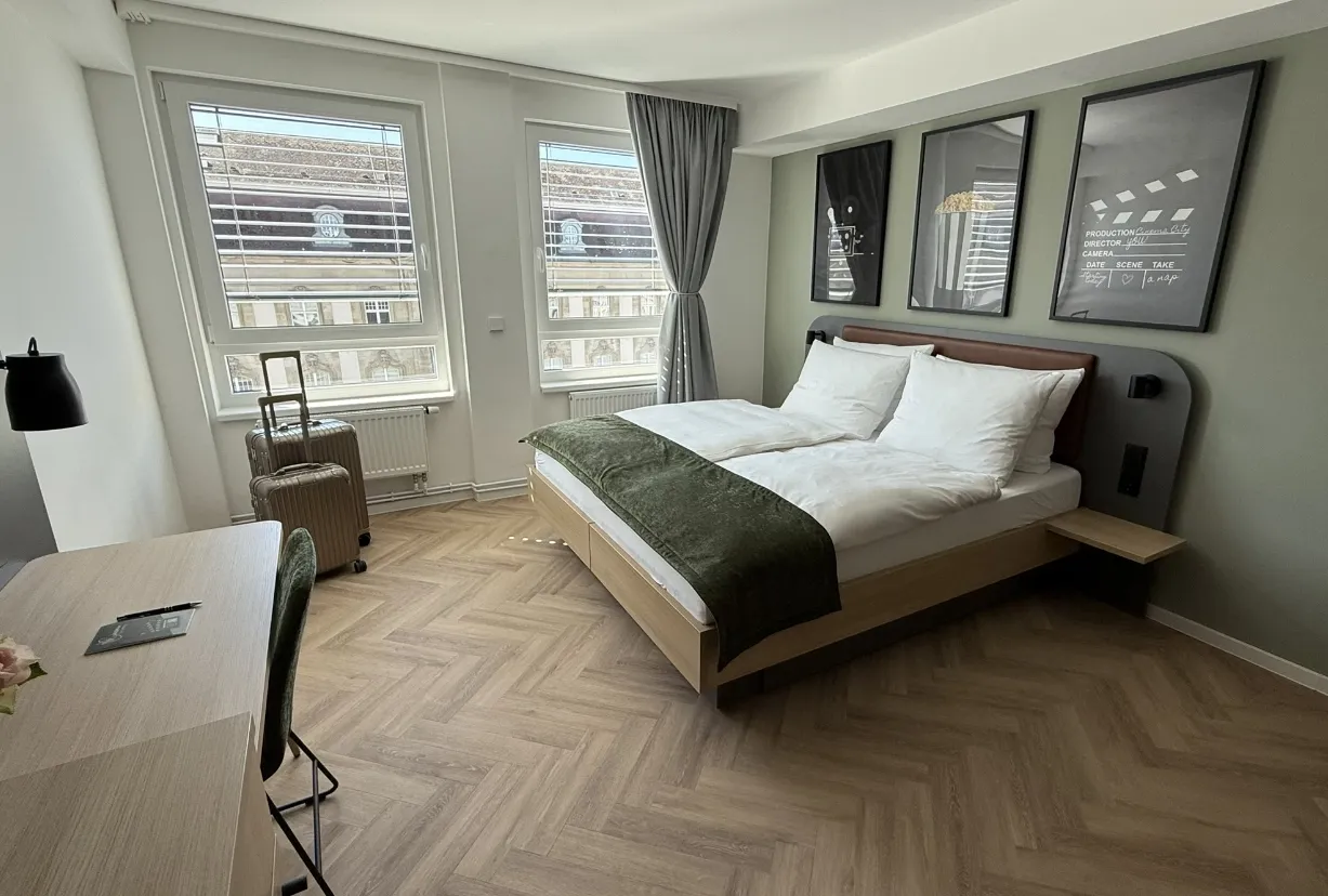 Helles Vierbettzimmer mit Doppelbett, Stockbett und großem Fenster im Cinema City Hotel