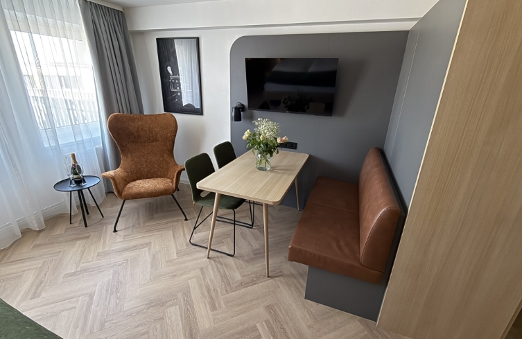 Sitzecke mit Fernseher, Esstisch und bequemen Sesseln – für entspannte Stunden im Zimmer