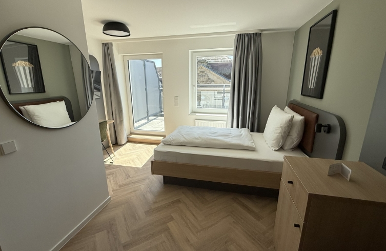 Einzelzimmer mit modernem Bett und hellem Tageslicht, ideal für Alleinreisende