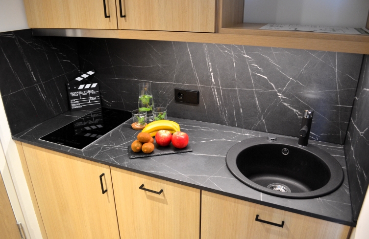 Kleine Küchenzeile mit Spüle, Obst, Getränk und Filmklappe – ideal für längere Aufenthalte