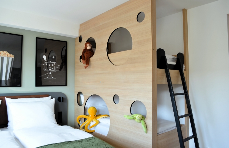 Familienzimmer mit Hochbett, Spielwand mit Kletterelementen und Kuscheltieren im Kino-Stil